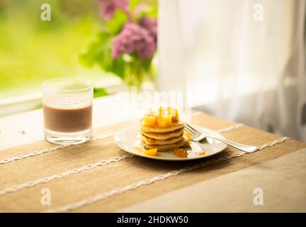 Pancake con pesca tagliata a colazione, persona in background Foto Stock