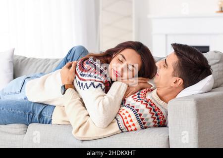 Felice giovane coppia che indossa maglioni caldi a casa Foto Stock