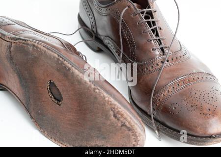 Studio girato di vecchio, stanco e poco graffiato cappuccio punta pizzo op scarpe oxford in marrone brunito, su sfondo bianco. Foro nella suola del Foto Stock