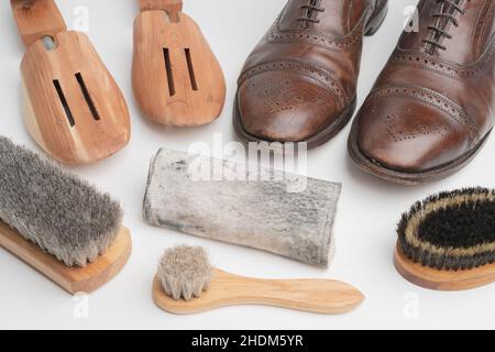 Studio girato di vecchio, stanco e poco graffiato cappuccio punta pizzo op scarpe oxford in marrone brunito, su sfondo bianco. Tre spazzole di diverso Foto Stock