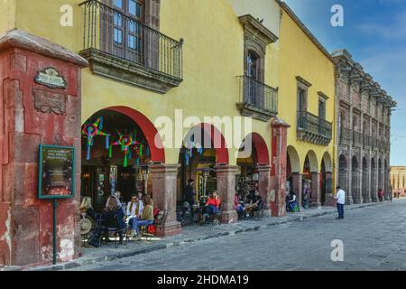 La gente si rilassa intorno ai caffè all'aperto e ristoranti nel quartiere centrale lungo il portale Allende, nella coloniale San Miguel de Allende, MX Foto Stock