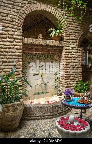 servizio di tè alla menta in un rinfrescante cortile in pietra con fontane e piante Foto Stock