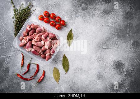 Cuori di pollo crudi di di carne fresca in contenitore di plastica, su sfondo grigio tavola di pietra, vista dall'alto piatto, con spazio per la copia del testo Foto Stock