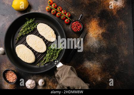 Cotolette di pesce crudo fatte di pesce in pangrattato, su vecchio sfondo rustico scuro tavolo, vista dall'alto piatto, con spazio di copia per il testo Foto Stock