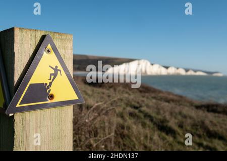 Segno giallo e nero di avvertimento del pericolo di erosione sul bordo della scogliera che domina Seven Sisters a Hope Gap, eaford nel Sussex orientale, Regno Unito. Foto Stock