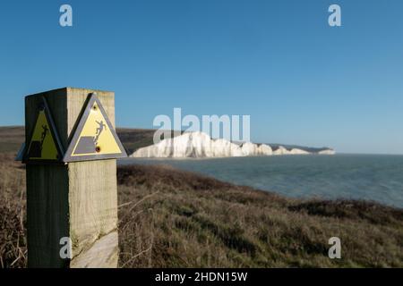 Segno giallo e nero di avvertimento del pericolo di erosione sul bordo della scogliera che domina Seven Sisters a Hope Gap, eaford nel Sussex orientale, Regno Unito. Foto Stock