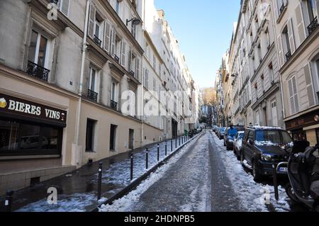 Strada stretta vuota tra gli edifici di appartamenti con auto parcheggiate in una giornata invernale nevosa e fredda Foto Stock