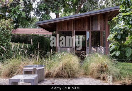 Bella piccola capanna di legno. Verde giardino gioia in estate con pietra e pianta di ryegrass perenne. Rilassatevi in giardino e godetevi il bel tempo. Foto Stock