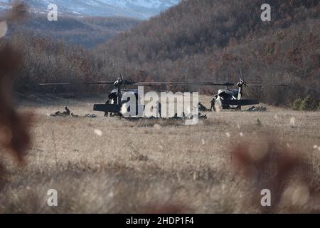 US Army UH-60L Blackhawks appartenente Ad Una Compagnia, 1st Battaglione 169th Regiment Aviazione e troopers appartenenti a 1st Squadron 172nd Cavalry Regiment (montagna) tappa in una zona di atterraggio nella Babaj Boks Training Area, Kosovo 21 dicembre 2021. I soldati hanno partecipato a 'Alpine Swarm', un esercizio di formazione per mantenere la disponibilità a tutte le contingenze, migliorando al contempo l'interoperabilità multinazionale. Questa immagine è stata ritagliata elettronicamente e migliorata eticamente per enfatizzare il soggetto e non rappresenta male in alcun modo il soggetto o l'immagine originale. (STATI UNITI Foto dell'esercito dello staff Sgt. J Foto Stock