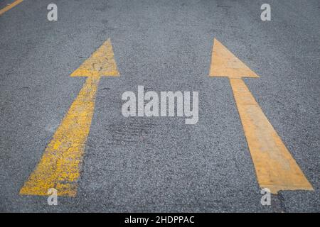 Due frecce gialle vecchio e nuovo directionon asfalto fondo strada Foto Stock