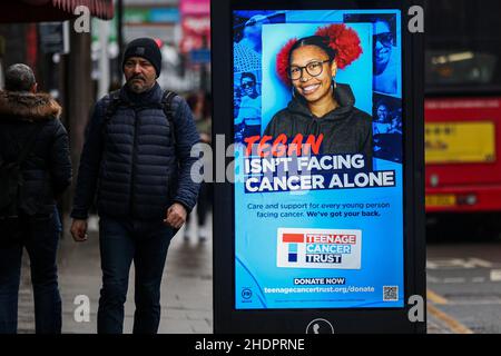 Londra, Regno Unito. 24th Dic 2021. Un uomo passa davanti a un annuncio digitale Teenage Cancer Trust a Londra. (Foto di Dinendra Haria/SOPA Images/Sipa USA) Credit: Sipa USA/Alamy Live News Foto Stock