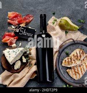 Sirah vino rosso con antipasti su sfondo grigio. Bevande alcoliche tradizionali. Vista dall'alto, piatto Foto Stock