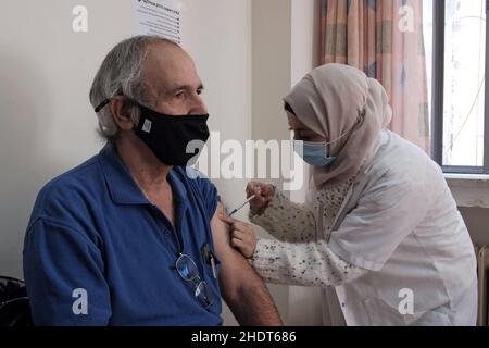 Gerusalemme, Israele. 6th Jan 2022. Un operatore sanitario arabo israeliano amministra il vaccino Pfizer-BioNTech COVID-19 a un anziano presso la clinica Leumit Health Services mentre Israele diventa il primo paese al mondo ad intraprendere una quarta campagna di vaccinazione COVID-19 il 6 gennaio 2022 a Gerusalemme, Israele. Israele ha iniziato a somministrare quarta dose di vaccino contro il coronavirus di Pfizer a persone di età superiore ai 60 anni e agli operatori sanitari, come parte degli sforzi per arginare il rapido aumento dei tassi di infezione causato dalla variante Omicron. Credit: Eddie Gerald/Alamy Live News Foto Stock