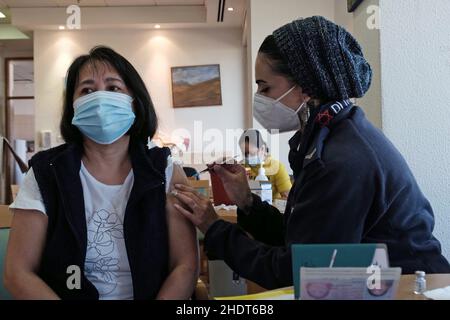 Gerusalemme, Israele. 6th Jan 2022. Un paramedico del Magen David Adom, il servizio medico di emergenza nazionale di Israele, amministra il vaccino Pfizer-BioNTech COVID-19 ad un caregiver filippino nella casa di cura di Migdal Nofim mentre Israele diventa il primo paese al mondo ad intraprendere una quarta campagna di vaccinazione COVID-19 il 6 gennaio 2022 a Gerusalemme, Israele. Israele ha iniziato a somministrare quarta dose di vaccino contro il coronavirus di Pfizer a persone di età superiore ai 60 anni e agli operatori sanitari, come parte degli sforzi per arginare il rapido aumento dei tassi di infezione causato dalla variante Omicron. Credit: Eddie Gerald Foto Stock