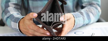 La donna mostra un portafoglio vuoto sulle monete e sui documenti da tavola Foto Stock