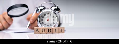 Audit e indagini antifrode. Auditor che utilizza la lente di ingrandimento sul documento Foto Stock