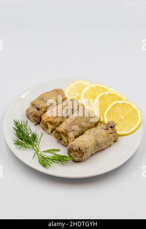 Foglie di cavolo farcite, in un piatto di ceramica. Involtini di cavolo vegano, foglie di cavolo cotte, avvolti intorno a un ripieno di riso, cipolle e spezie. (Lahana s Foto Stock