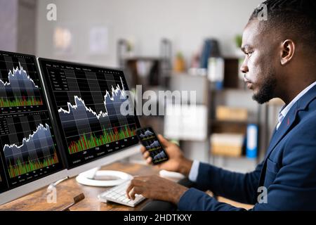 Analista di mercato azionario presso l'ufficio utilizzando più schermi Foto Stock