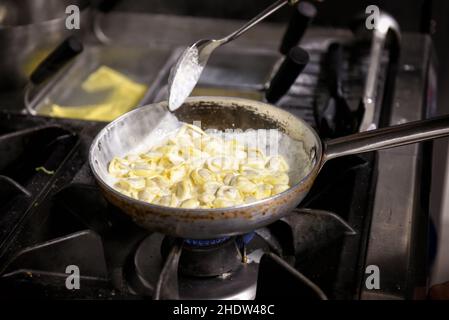 I tradizionali tortellini italiani vengono cotti in padella su un assortimento di ripieno di carne e salsa al formaggio Foto Stock