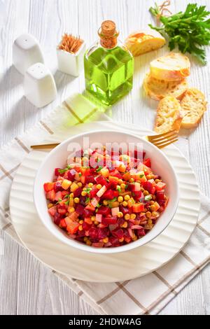 Vinegret, vinaigrette russe, insalata di verdure cotte a dadini barbabietole rosse, patate, carote, cipolle tritate, sottaceti, piselli verdi in un bone bianco Foto Stock