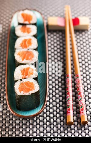 Da sopra di rotolini di sushi hosomaki freschi sul piatto posto vicino ai bastoncini di chopstick sul tavolo Foto Stock