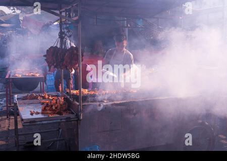 Venditore di strada cambogiano allo stallo di strada di carne di Smokey BBQ durante il Capodanno cinese, mercato di Kandal, Phnom Penh, Cambogia. © Kraig Lieb Foto Stock