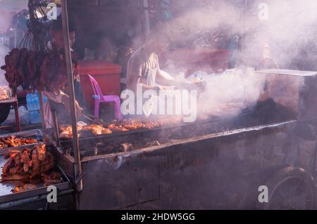 I venditori ambulanti cambogiani al macedone di carne di Smokey durante il capodanno cinese, mercato di Kandal, Phnom Penh, Cambogia. © Kraig Lieb Foto Stock