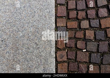 Vista perpendicolare di un pavimento di piastrelle di porfido e lastre di pietra in una piazza italiana medievale Foto Stock