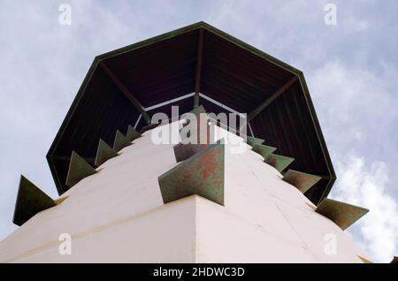 Foto di scorta di un faro visto dal basso. Faro alto, arrugginito e vecchio su una spiaggia di tarragona, Spagna. Torre alta sotto una giornata nuvolosa. Foto Stock