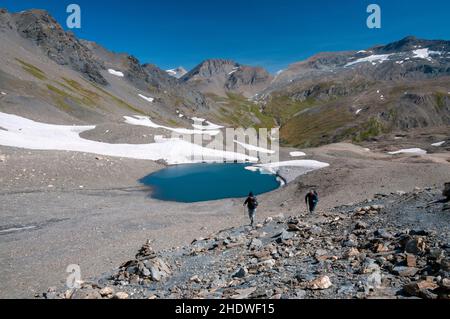 Escursionisti presso il lago dell'antico ghiacciaio la Jave con cima Signal de l'Iseran (3237m) e passo di montagna pers sullo sfondo, massiccio della Vanoise, Hau Foto Stock