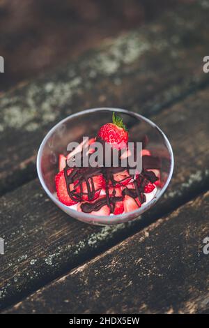 Un colpo verticale di budino con panna montata e fragole su un tavolo di legno Foto Stock