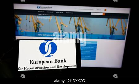 Persona che tiene il cellulare con il logo della Banca europea per la ricostruzione e lo sviluppo (BERS) sullo schermo con il sito web. Mettere a fuoco sul display del telefono. Foto Stock