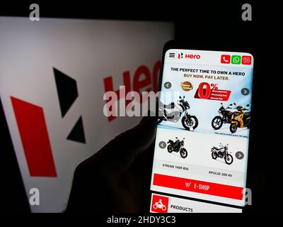 Persona che detiene il cellulare con sito web della società automobilistica indiana Hero MotoCorp Limited sullo schermo con logo. Concentrarsi sul centro del display del telefono. Foto Stock