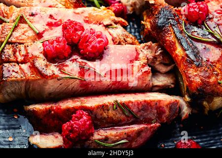 Bistecca di maiale arrosto su un piatto. Succosa bistecca affettata e marmellata di frutti di bosco Foto Stock