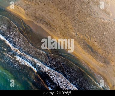 Vista dall'alto delle onde schiumose di acqua di mare pulita che si rotola su una spiaggia sabbiosa in una giornata di sole sul resort Foto Stock