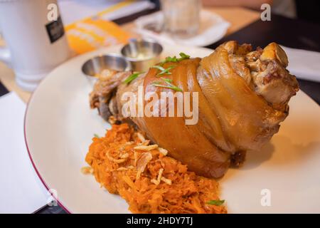 Arrosto di maiale eisbein fuso a snodo con brasato di Cavoli lessi e senape sul tagliere di legno Foto Stock