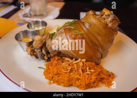 Arrosto di maiale eisbein fuso a snodo con brasato di Cavoli lessi e senape sul tagliere di legno Foto Stock