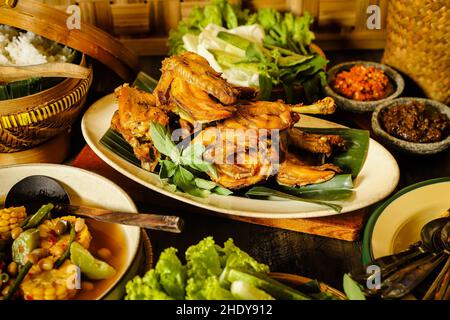 Ayam Goreng. Pollo fritto indonesiano servito con pasta di peperoncino, verdure e riso al vapore Foto Stock
