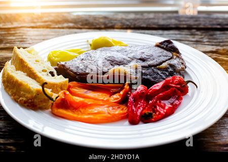 Bistecca club con peperoni dolci grigliati su piatto bianco Foto Stock