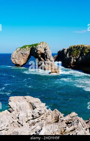 Vista panoramica delle onde che si infrangono sulla costa rocciosa contro il cielo blu. Castro de las Gaviotas (Forte dei Seagulls) e Spiaggia del Huelga, Llanes Foto Stock