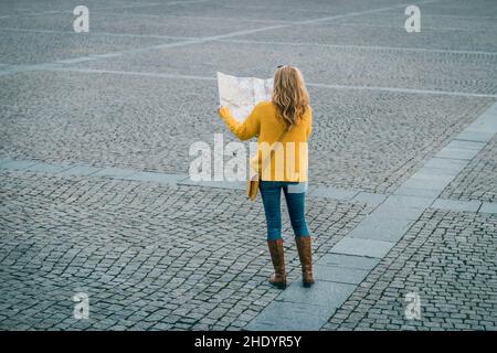 Turista perso in città. Donna che guarda alla mappa della città e cerca di trovare la strada. Concetto di viaggio Foto Stock