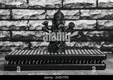 Statua di pietra di Lord Ganesha, indù God.Close-up nero Sadhu tavole di legno con chiodi per yoga, pratiche spirituali su sfondo grigio e scuro br Foto Stock