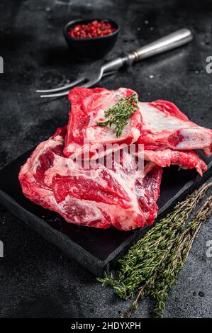 Costolette di manzo di vitello, sparerib crudo su tavola di marmo. Sfondo nero. Vista dall'alto Foto Stock