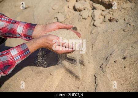 Cava di sabbia nelle mani di un uomo. Messa a fuoco selettiva. Foto Stock