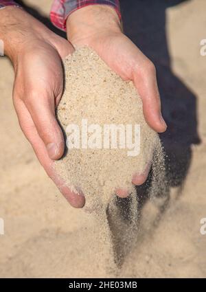 Cava di sabbia nelle mani di un uomo. Messa a fuoco selettiva. Foto Stock