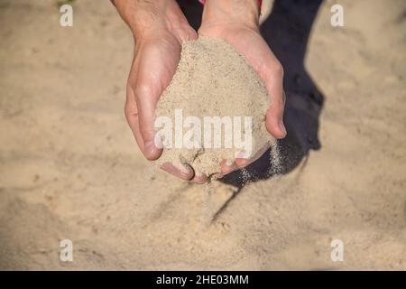 Cava di sabbia nelle mani di un uomo. Messa a fuoco selettiva. Foto Stock