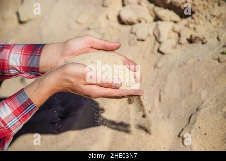 Cava di sabbia nelle mani di un uomo. Messa a fuoco selettiva. Foto Stock