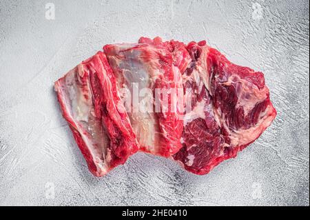 Costolette di manzo, carne cruda sul tavolo da cucina. Sfondo bianco. Vista dall'alto Foto Stock