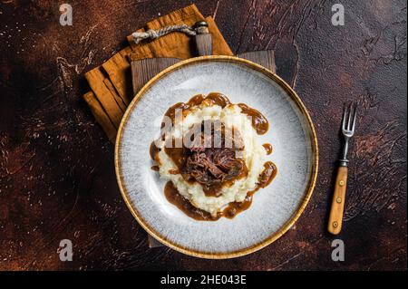 Guance di manzo cotte lentamente in salsa di vino rosso con purè di patate. Sfondo scuro. Vista dall'alto Foto Stock