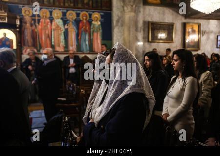 I cristiani palestinesi partecipano a una preghiera di messa presso la chiesa greco-ortodossa di San Porfirio. La maggior parte dei credenti ortodossi festeggia il Natale il 7 gennaio. Le chiese in Romania, Bulgaria, Cipro e Grecia lo segnano il 25 dicembre insieme ad altre denominazioni cristiane. Foto Stock